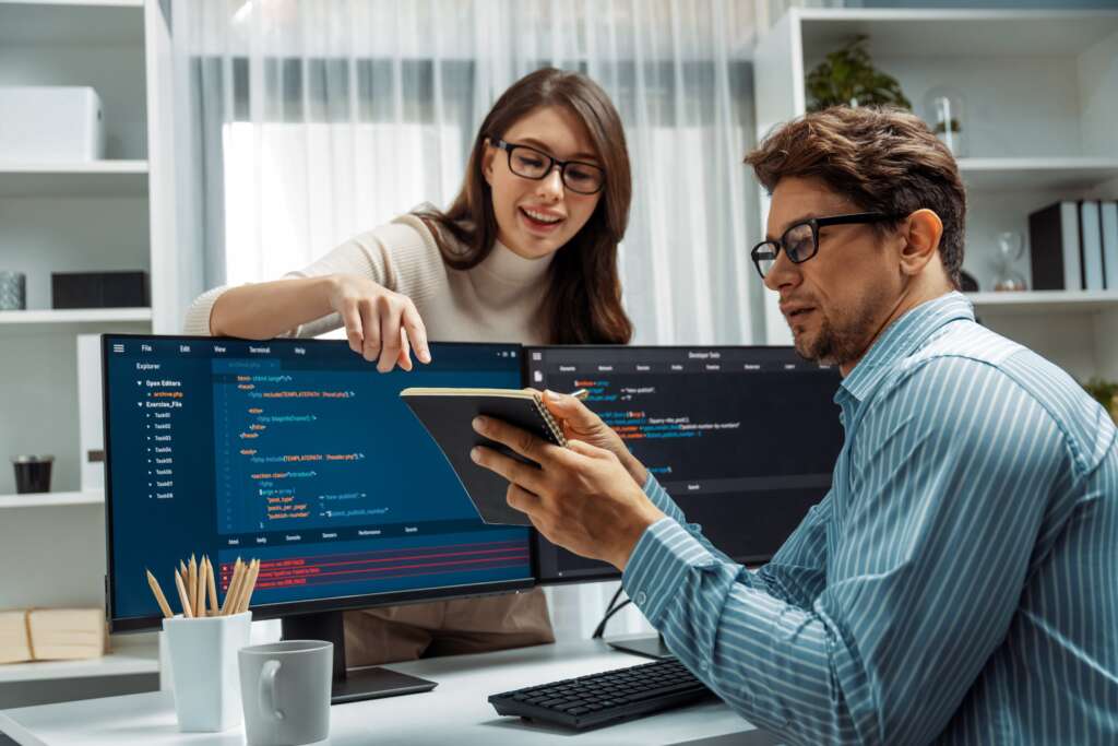 woman-standing-opposite-man-programmer-working-desk-discuss-for-software-development